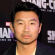 A close-up on Simu Liu on a red carpet with Marvel's Shang-Chi and the Legend of the Ten Rings logos behind him.
